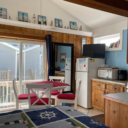 Small kitchen and dining area with nautical decor, wood cabinets, and a sliding glass door leading to an outdoor deck.