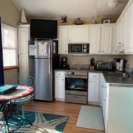 Bright kitchen with white cabinets, stainless steel appliances, round dining table, and blue accents.