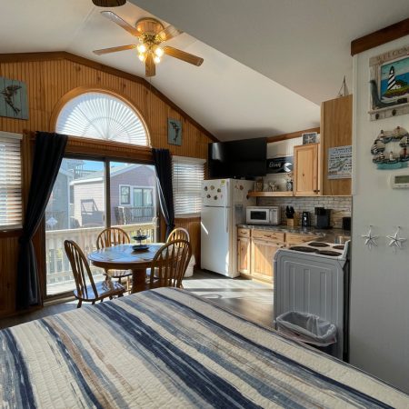 Small kitchen and dining area in a cozy, sunlit studio with nautical decor and wood paneling.