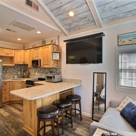 Modern kitchen with light wood cabinets, stainless appliances, a breakfast bar, and a small adjacent seating area.
